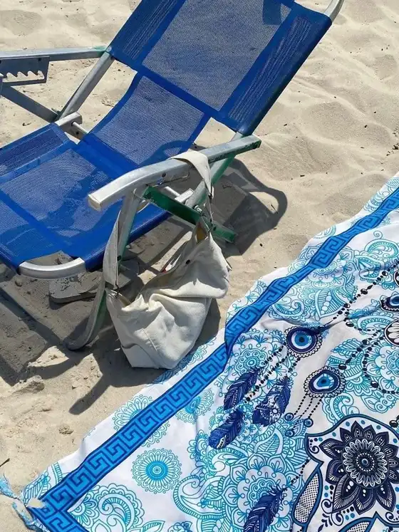 Cadeira de praia e canga estendida na areia