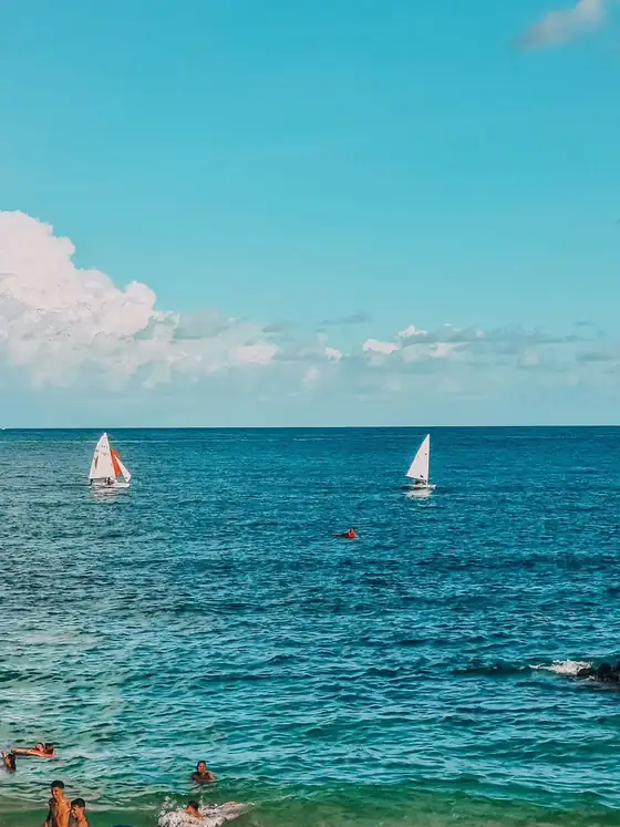 Mar turquesa com guarda-sóis e barcos ao fundo